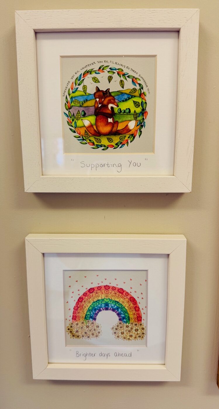 Two framed prints on the playroom wall, one of a fox reading 'Supporting You' and one of a rainbow reading 'Brighter days ahead'