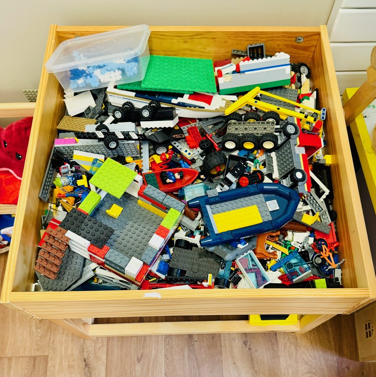 A wooden table filled with Lego bricks and part-built models