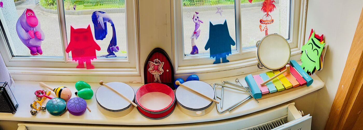 Children's musical instruments, drums, a xylophone and a tambourine, on a sunny windowsill